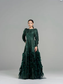  Woman wearing a hunter green sequin drop waist gown with a dramatic feather bottom detail.