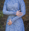 Woman wearing modest fitted blue floral lace gown with long sleeves.