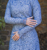 Woman wearing modest fitted blue floral lace gown with long sleeves.