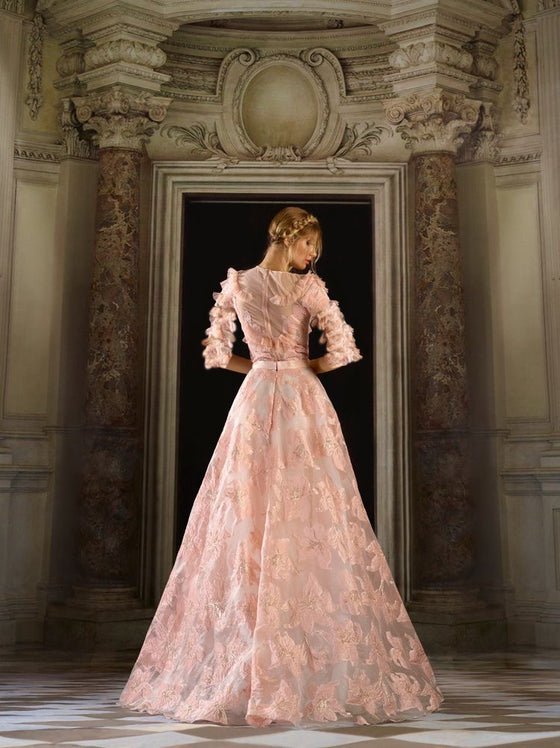 Woman wearing a blush pink modest ball gown with a tiered top and floral ball gown skirt.