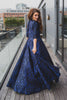 Woman wearing modest cobalt blue and black ball gown with cropped bolero. The three-quarter sleeve bolero has a large bow detail in front and mini covered buttons cascading down the back.