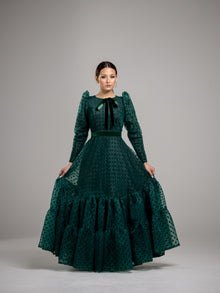  Woman wearing an elegant modest hunter green gown with velvet polka dots, a bottom tier and a green velvet bow at the neck. 