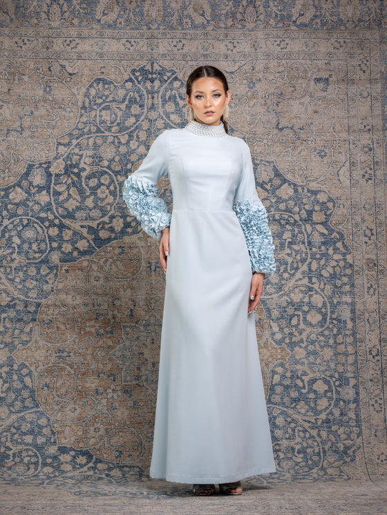 Woman wearing a modest powder blue gown with ruffled sleeves and a high neck pearl collar.