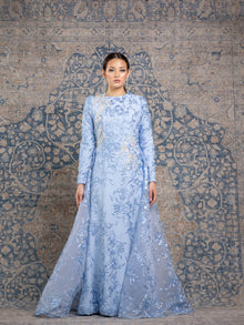  Woman wearing a modest powder blue floral long sleeve gown with a flowing skirt cape for added elegance.