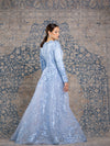 Woman wearing a modest powder blue floral long sleeve gown with a flowing skirt cape for added elegance.