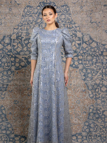  A woman wearing a sky blue modest gown with a silver honeycomb overlay and puff three quarter sleeves. 