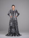 A woman wearing a black and white floral guipure open lace modest evening gown with long sleeves. 