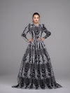 A woman wearing a black and white floral guipure open lace modest ball gown with full ball gown skirt and long sleeves. 