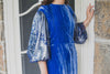 Woman wearing modest cobalt blue crushed velvet ruched gown with straight silhouette and billowy three-quarter length sleeves.