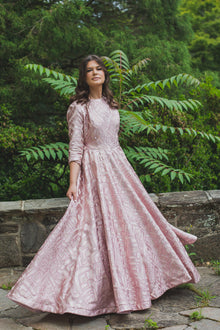  Woman wearing a modest blush pink ball gown with pink foiled geometric shapes and three-quarter length sleeves.