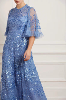  Woman wearing blue modest Needle & Thread with flare sleeves and beaded embellishments.