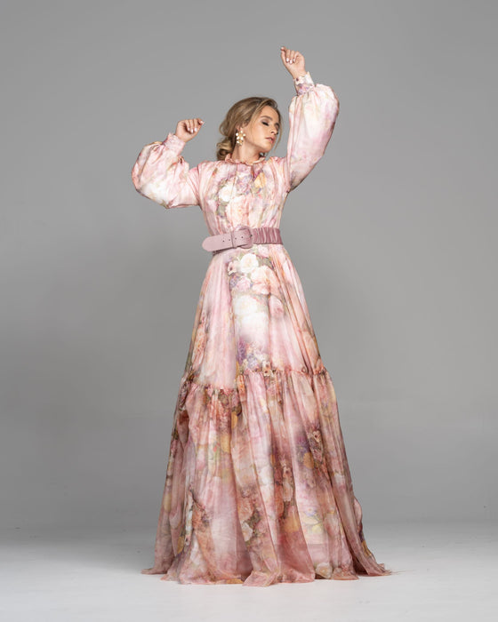 Woman wearing a modest pink floral garden print gown made from silk flowy fabric with a large stretchy buckle mauve belt.